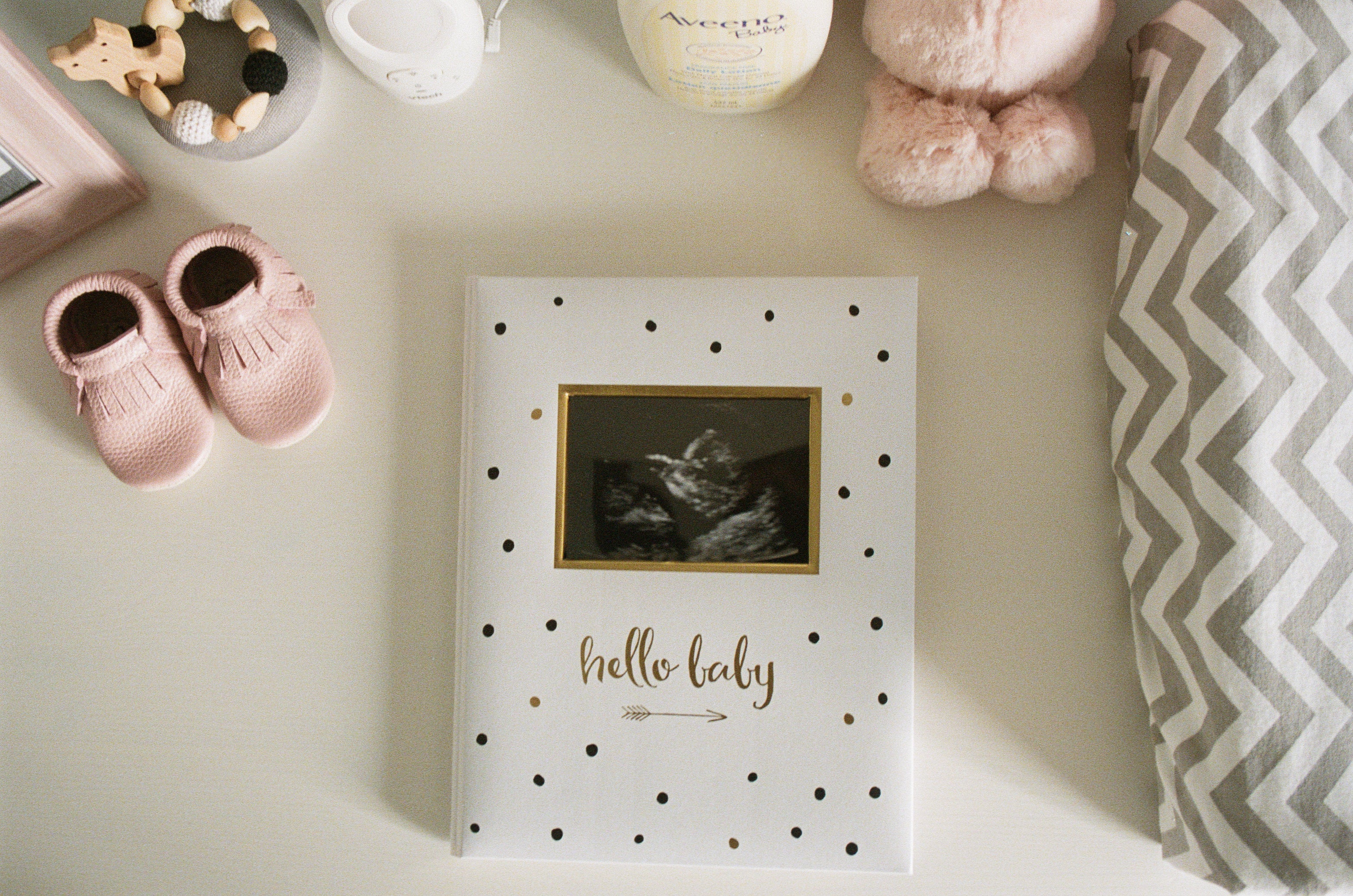 A flat lay image of a baby keepsake book with baby toys and shoes around it